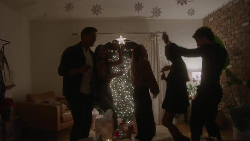 Friends dance and celebrate a christmas party in a living room