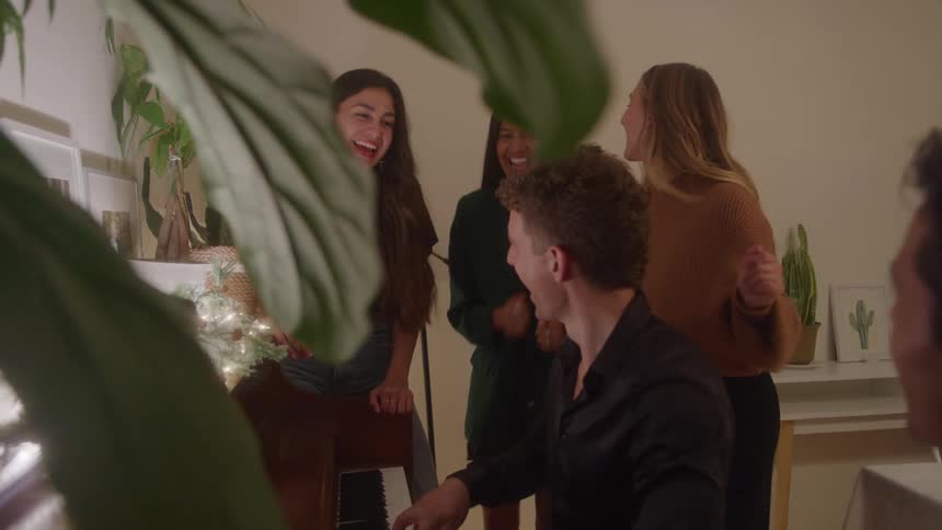 Group of friends enjoying music and laughter together playing piano indoors