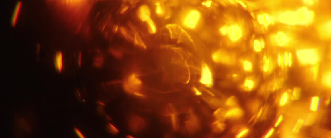 An array of bright blurry orange and yellow lights and flares swirling and moving around a dark background