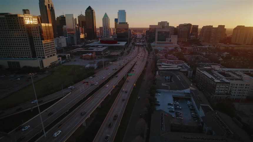 Aerial view of a city skyline at sunset with a busy highway