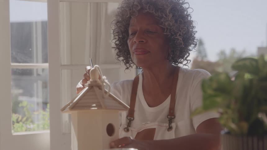 The woman is working on building a bird house