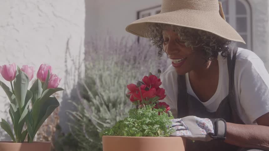 A woman tends to potted flowers while gardening outdoors
