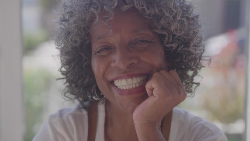 A closeup portrait of an older woman with a vibrant smile and a happy expression