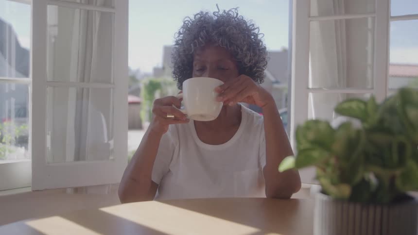 The woman drinks her coffee and smiles