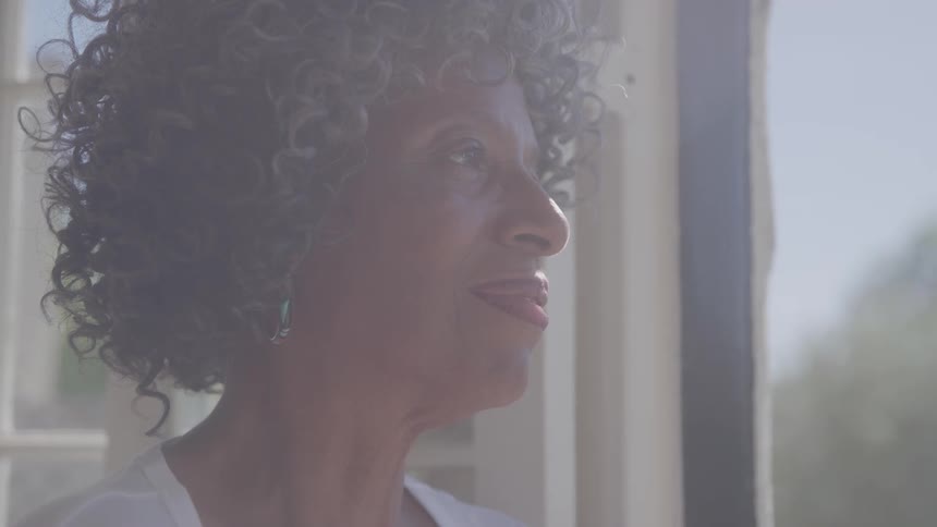 The woman smiles while peering out the window