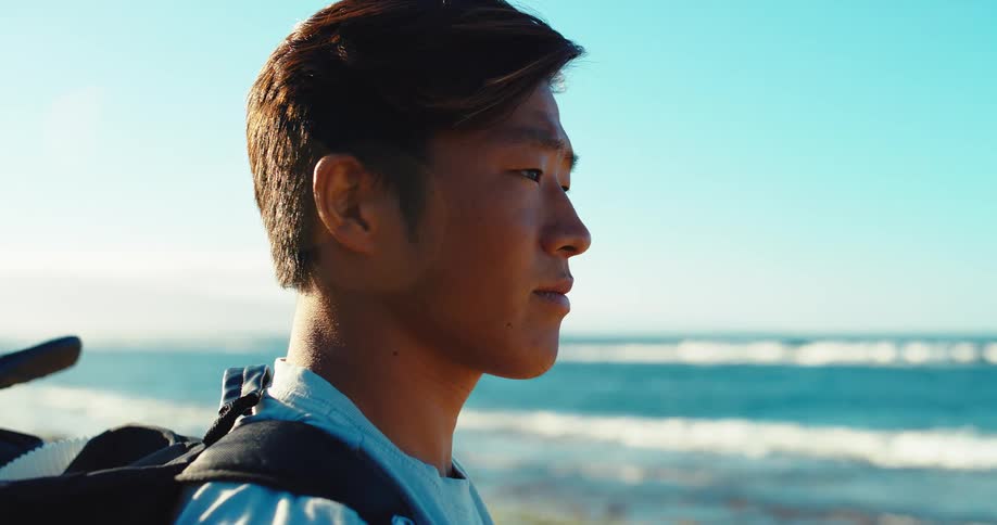 Man gazes at the horizon by the sea with a backpack on his shoulders