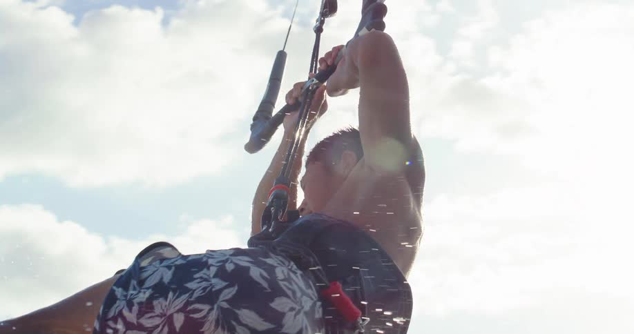 A man practicing kitesurfing making a big jump with his board