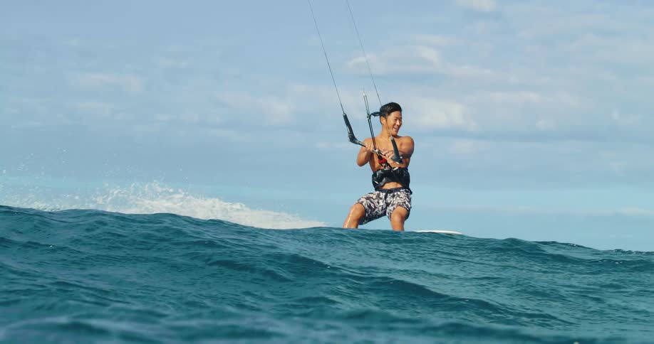 The person in the video is kitesurfing which involves using a large kite to harness wind power and pull a rider across the water on a board the kite is connected to the rider via a control bar and lines allowing them to steer and control their movement