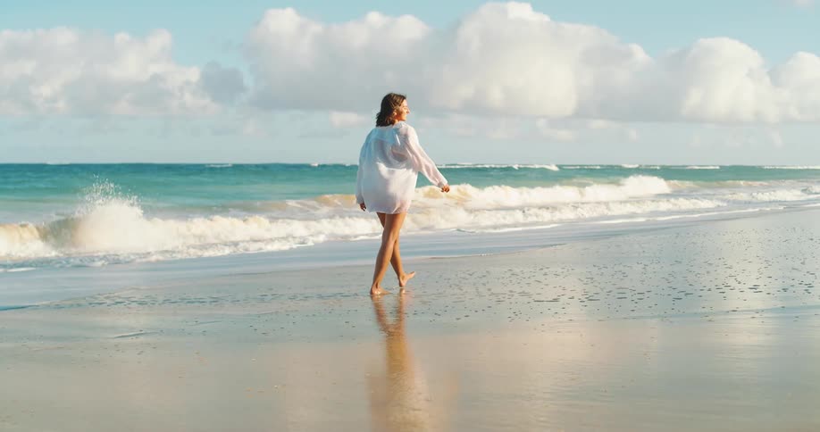 A woman walks along the beach enjoying the ocean view