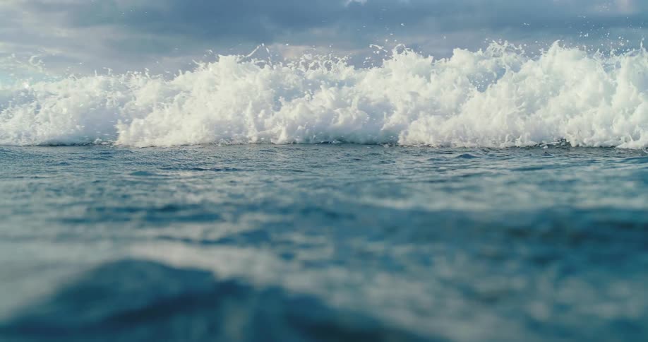 Waves splash as they roll into shore and the view moves underwater