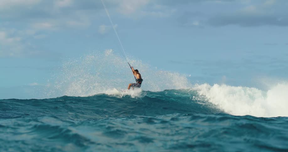 Kitesurfer rides a blue wave in the open sea