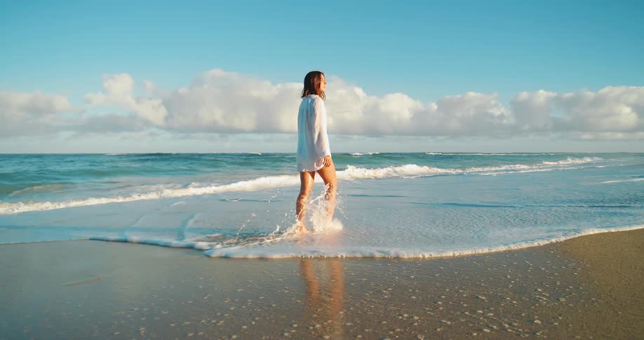 A young woman walking barefoot along the beach
