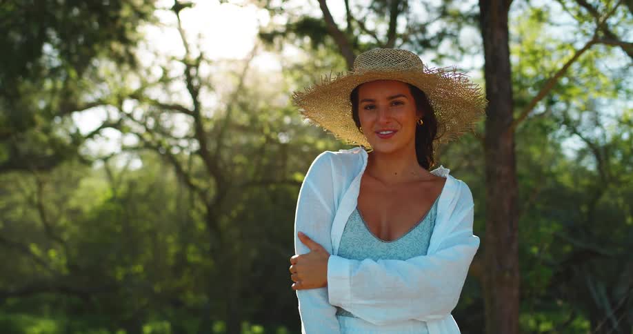 A woman is smiling by the trees on a windy day
