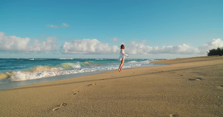 Woman walking alone along the sand of a deserted beach