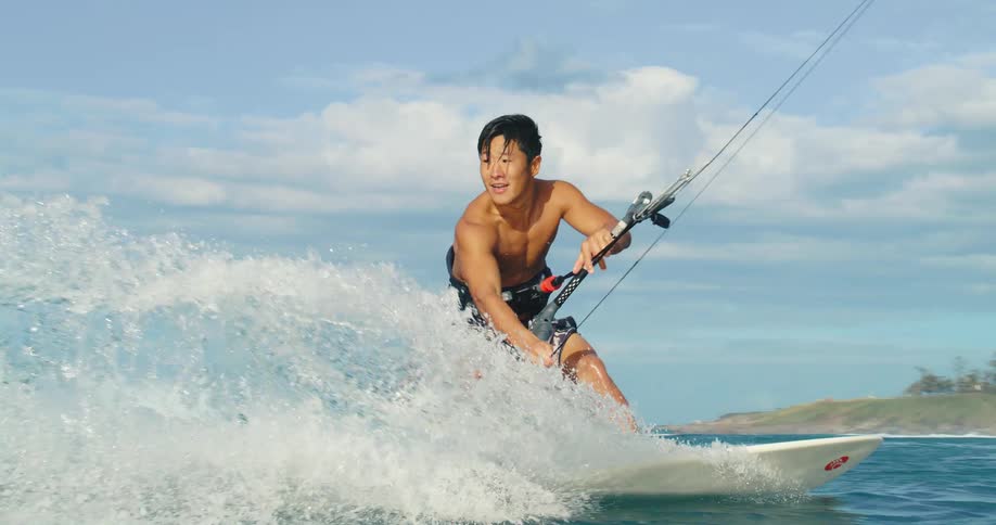 Man practices kitesurfing while maneuvering over the waves