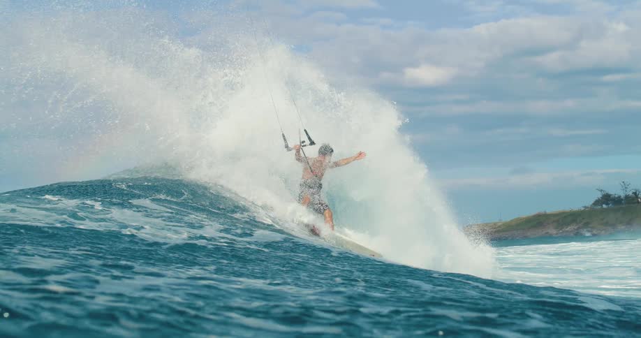 A man is kite surfing on a crashing ocean wave