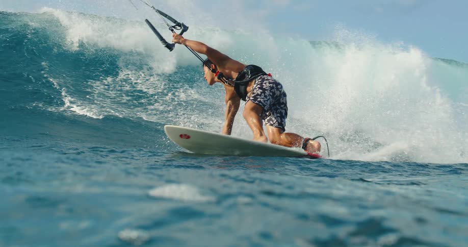 A man is kite surfing and riding a big wave