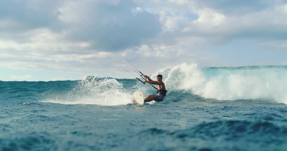 Man maneuvering a board while kitesurfing in rough sea