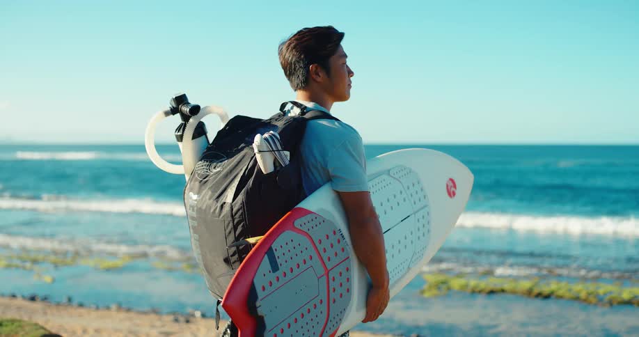 Man with backpack and diving gear looking at the ocean