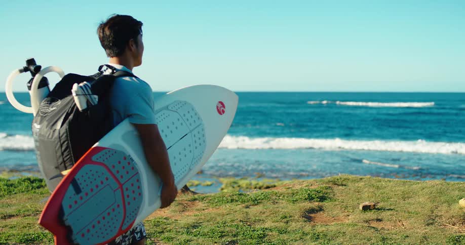 Man walking towards the sea with a surfboard
