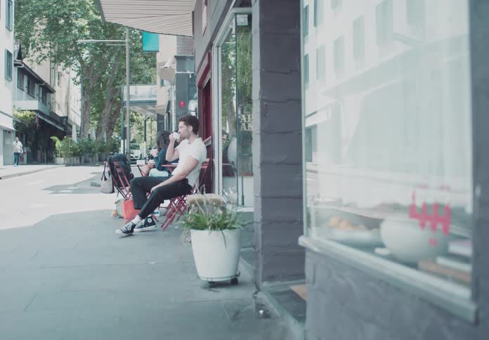 Three people casually sitting at a table outside a cafe enjoying a sunny day