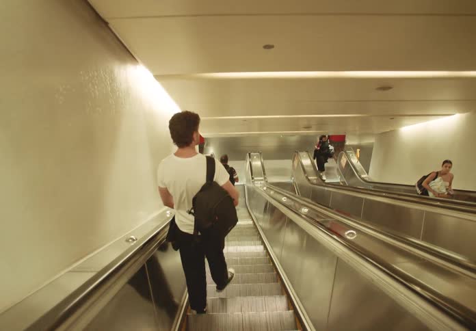 Man walks down the steps while riding on a downward escalator