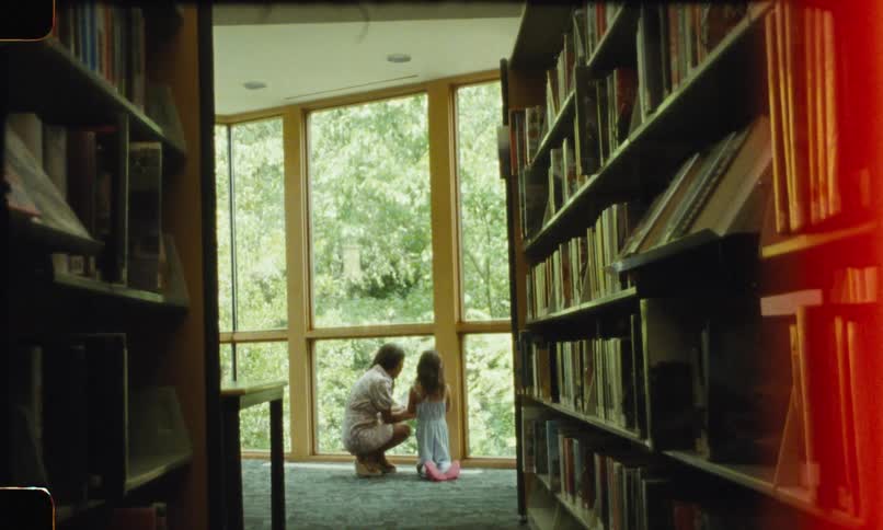 Mother and daughter near a large window inside a library