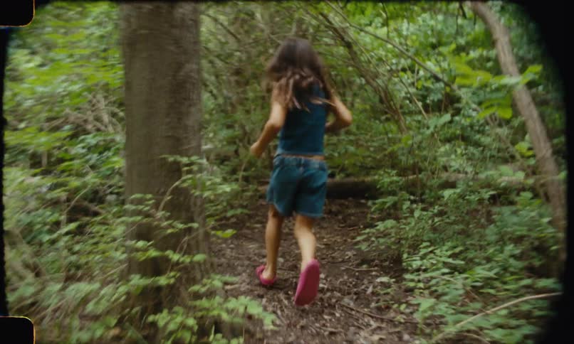 Child runs along a narrow trail in the dense forest