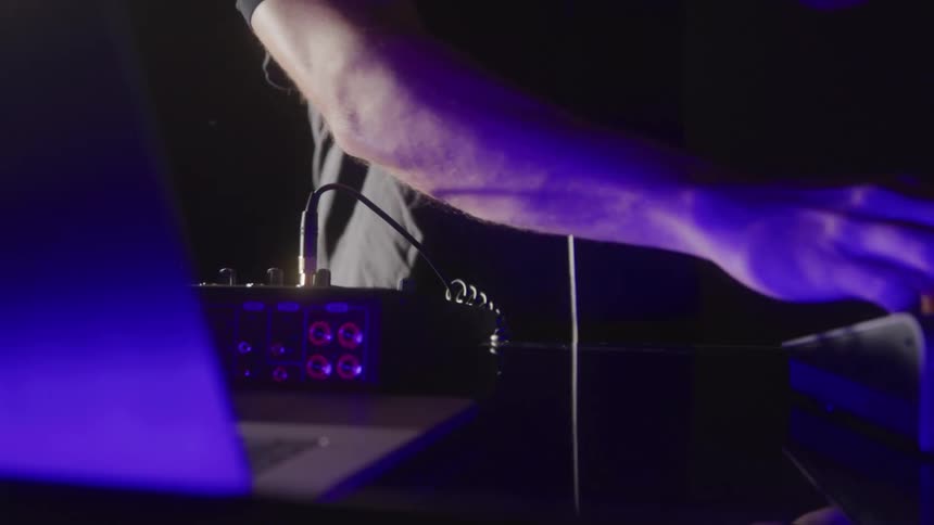 The dj is playing music from the soundboard