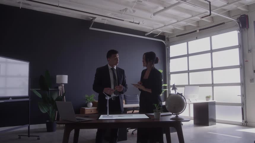 Two business professionals discuss work inside a modern office