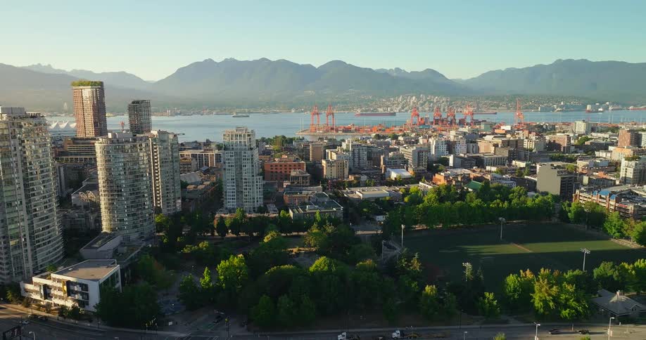 Aerial view of a city skyline with mountains and water in the background