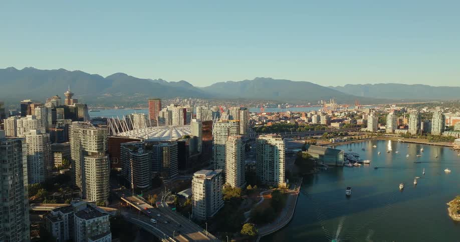 Based on the images from the video an aerial shot captures a modern cityscape with a large body of water in the foreground the city is surrounded by mountains and has several boats docked in the harbor