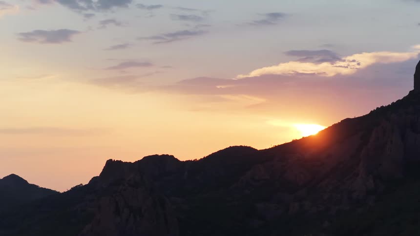 The sun glows on the horizon over a mountain
