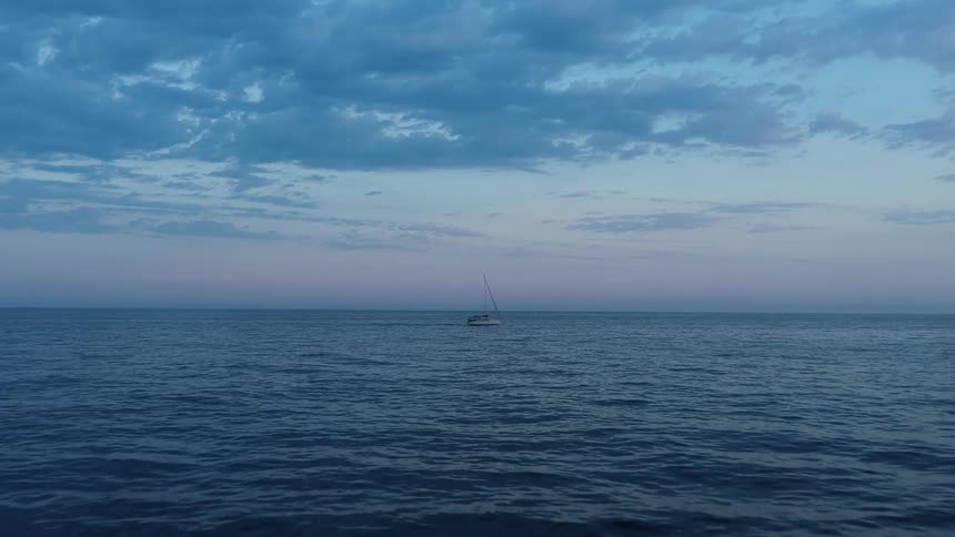 Lonely boat sailing on the horizon at sunset