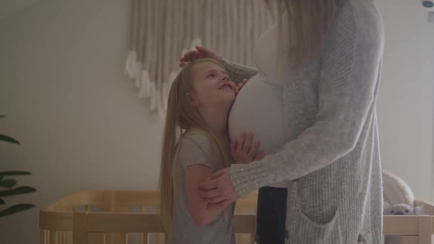 A daughter touches her pregnant mothers stomach
