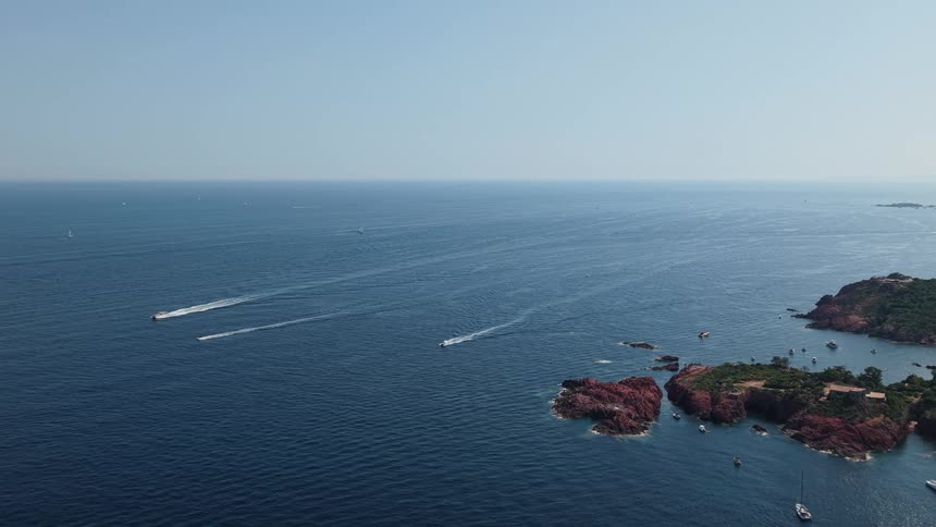 Boats sail on the water with rocks and islands along the coast