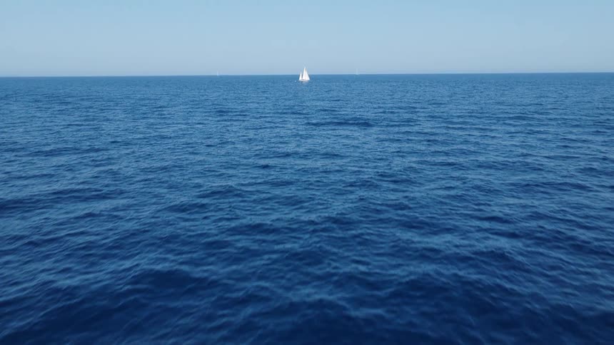 Water ripples and waves with a sailboat on the horizon