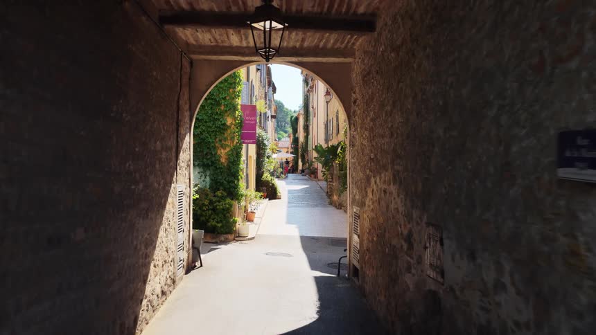 A stone archway opens onto a narrow european street