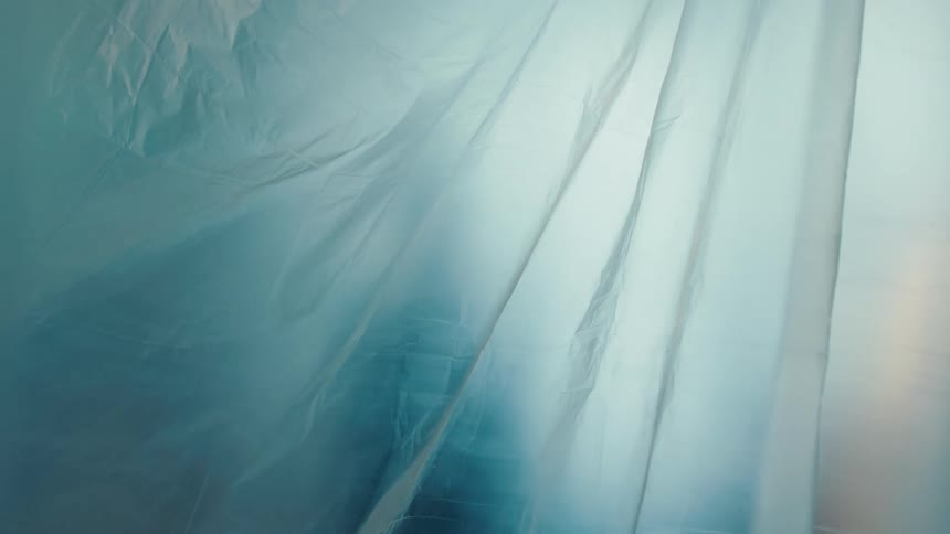 Silhouette of a person projected behind a translucent blue fabric