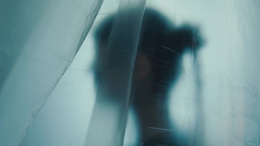 A mysterious shadowy silhouette of a person slightly moving behind a blurry translucent sheet