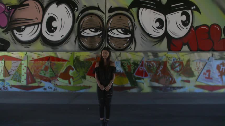 A young woman standing in front of an urban wall painted with street art