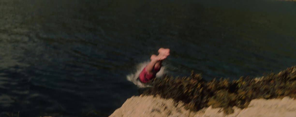Person dives off a cliff into the lake