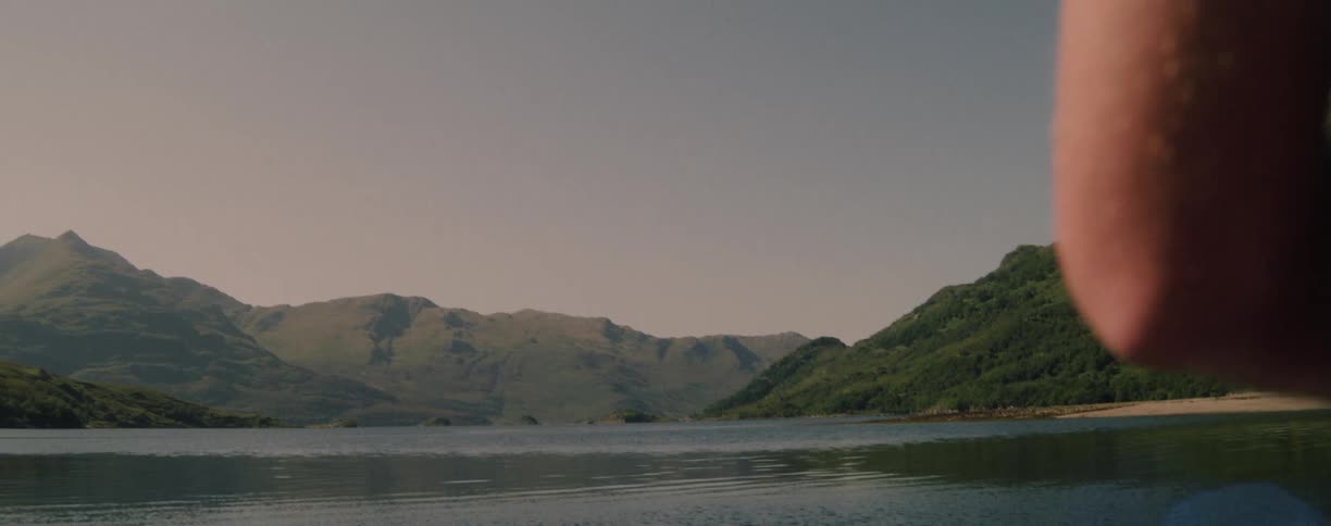 Man turns the reel of his fishing rod on the river in the mountain valley