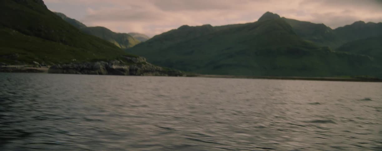 View from a boat moving across the water with mountains along the coast