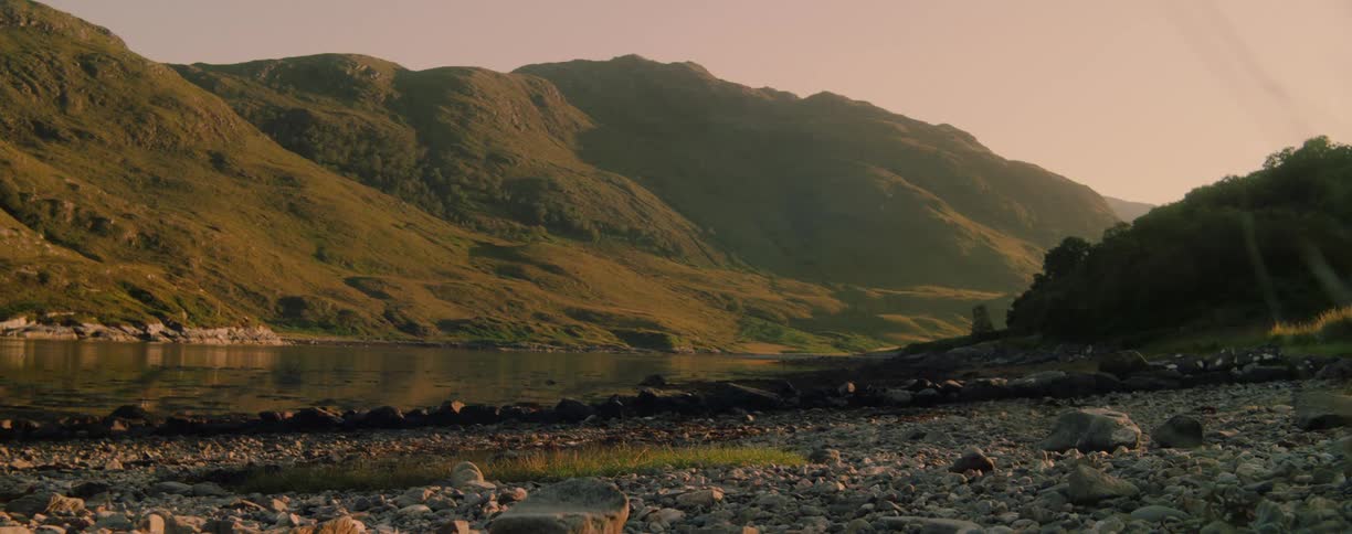 Green mountains reflected in a calm lake at sunset