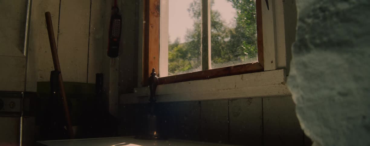 Sunlight streams through a dusty window in a rustic room