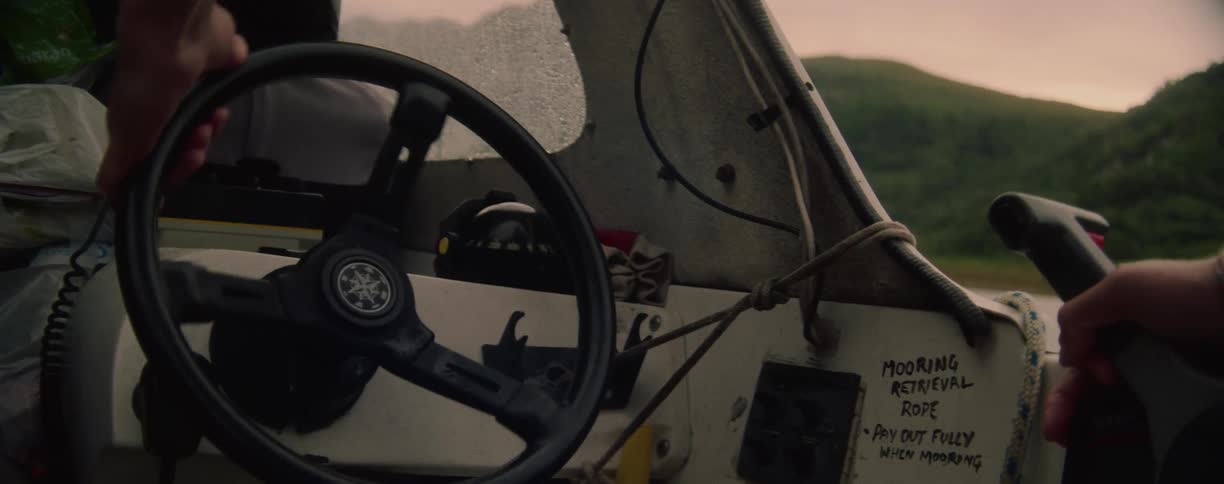 A person turns the steering wheel on the boat