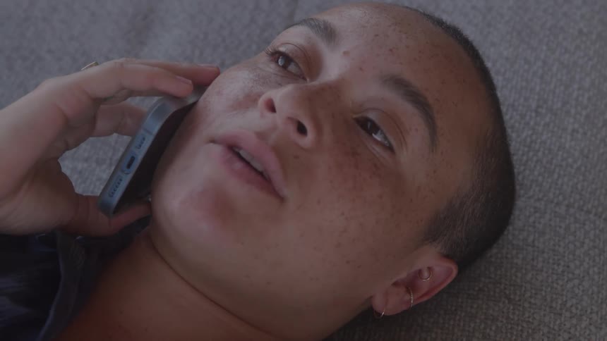 A woman lays down while talking on the phone