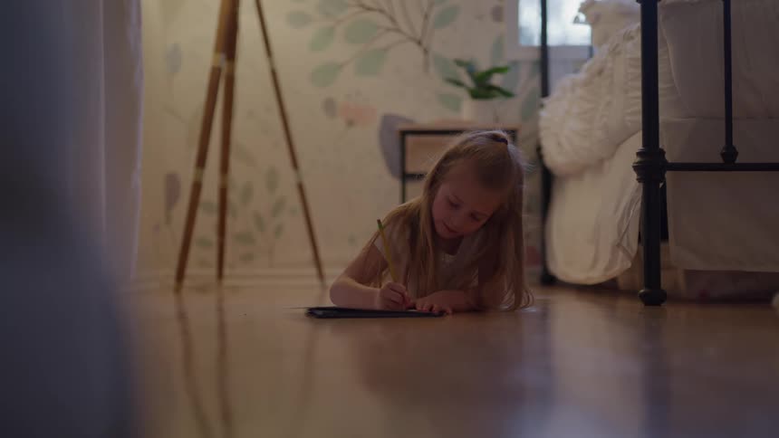 Little girl writing in a notebook on the floor of her bedroom