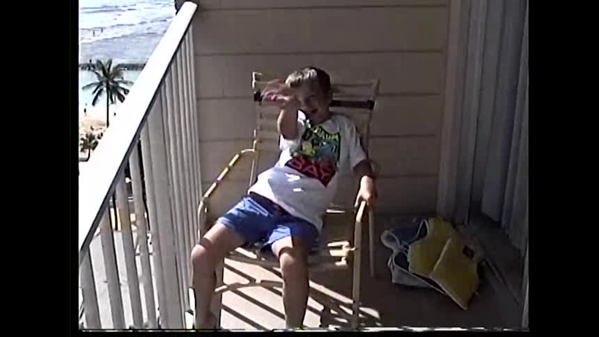 Child sitting on a balcony chair with an ocean view